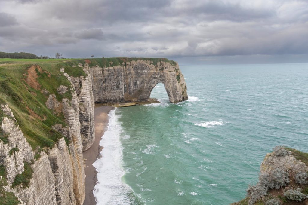 Breathtaking view of Étretats famous cliffs under a moody sky, showcasing natures beauty.